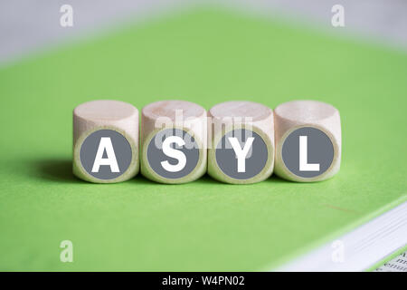 dice on a notebook forming the word "asylum" in German Stock Photo