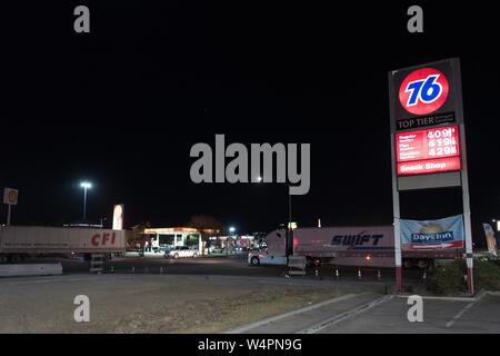 Signs for gas stations, including a Philips 76 station, are visible with semi trucks driving past at a truck stop along the 5 Freeway late at night in Lost Hills, California, October 19, 2018. () Stock Photo