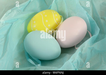 Pastel colored Easter eggs ornaments with ribbons in blue tissue paper Stock Photo