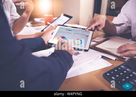 Asian businesswomen using tablet for analysis documents and graph financial diagram working in meeting Stock Photo