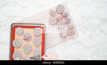 Step by step. Flat lay. Cooling freshly baked bake red, white, and blue pinwheel sugar cookies on a cooling rack. Stock Photo