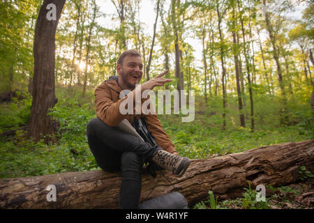 one young man, laughing in forest alone, pointing finger. Stock Photo