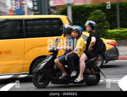 July 24, 2019, Taipei, Taiwan: A scooter carrying three people can be seen at a local street near Taipei Main station. Taipei is the capital and a special municipality of Taiwan. Located in the northern part of the island of Taiwan. According to Wikipedia, the city is home to an estimated population of 2,704,810 people. In Taipei you can still see old structures and buildings, but the city also seems to be making very rapid progress in its modern infrastructure. Photograph taken on Wednesday, July 24, 2019. Photo by: Ramiro Agustin Vargas Tabares. (Credit Image: © Ramiro Agustin Vargas Tabares Stock Photo