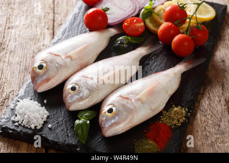 Raw pink dorado fish with spices, vegetables and lemon close-up on a slate board on the table. horizontal Stock Photo