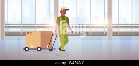 courier in uniform pushing trolley with cardboard box express delivery service concept african american worker with hand truck modern office hall Stock Vector