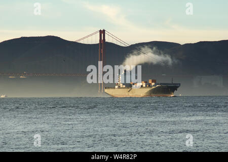 SAN FRANCISCO, CALIFORNIA, UNITED STATES - NOV 25th, 2018: A fast moving cargo container ship, entering San Francisco Bay, sailing underneath the Stock Photo