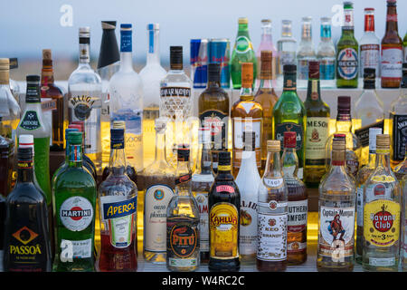 Various colourful alcoholic drink bottles lined up on a shelfs at a pub bar tavern in Cyprus. Stock Photo