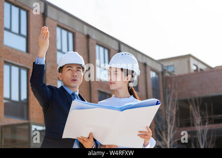 Two architects talking over blueprints, Beijing, China Stock Photo
