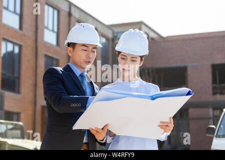 Two architects talking over blueprints, Beijing, China Stock Photo