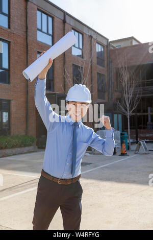 Male architect wearing safety helmet holding blueprints, Beijing, China Stock Photo