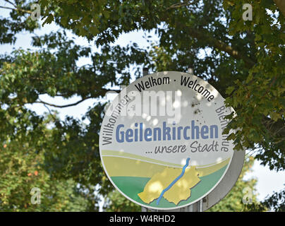 Geilenkirchen, Germany. 25th July, 2019. A sign with the inscription 'Welcome' in several languages and 'Geilenkirchen. our city' stands on the outskirts of the village. The German Weather Service (DWD) wants to clarify today whether the maximum temperature of 40.5 degrees measured at a measuring station in Geilenkirchen will be officially recognized. The measuring point does not belong to the DWD network. Credit: Caroline Seidel/dpa/Alamy Live News Stock Photo