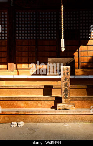 Sunlit wooden entrance steps to temple with white thongs left below, Hida-Takayama, Takayama, Gifu Prefecture, Japan Stock Photo