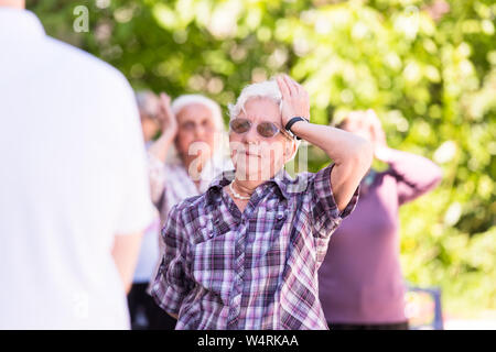 healthy senior woman exercising with friends in front of retirement home Stock Photo