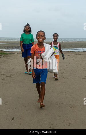 July 24, 2019, Cartagena, Bolivar, Colombia: A young boy smiles while carrying a sack of plastic waste at the La Boquilla during a clean-up session in Cartagena.Fundacion CoraJeM works in educating and creating opportunities for the people in need. Teaching them culture and values, it allows them to build up a better future and live with more dignity. Credit: Enzo Tomasiello/SOPA Images/ZUMA Wire/Alamy Live News Stock Photo