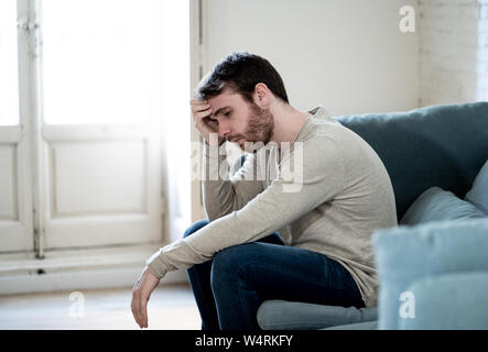 Unhappy depressed caucasian male sitting and lying in living room couch feeling desperate a lonely suffering from depression. In stressed from work, a Stock Photo