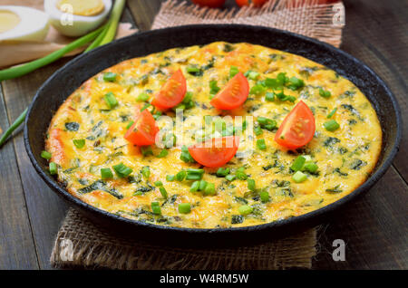 Vegetarian frittata with green onions and slices tomato in frying pan Stock Photo