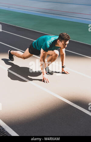 mixed race sportsman on start position at stadium