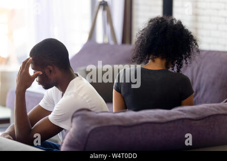 Rear view black couple sitting separately on couch not talking Stock Photo