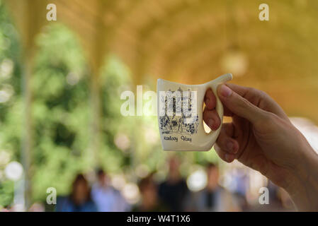 Man holding special mug for water from hot mineral spring in Karlovy Vary Stock Photo