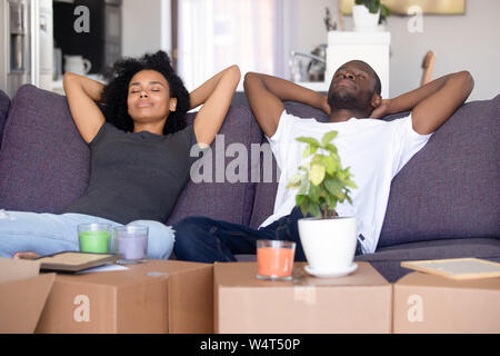 Tranquil african millennial couple resting on couch on moving day Stock Photo