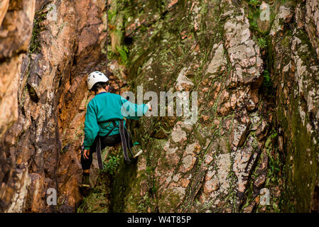 The little boy in the helmet climbs the rock Stock Photo