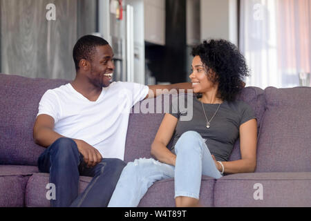 Couple sitting on couch talking spending time together at home Stock Photo
