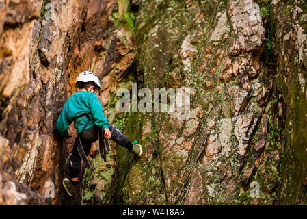 The little boy in the helmet climbs the rock Stock Photo