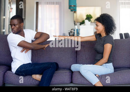 American angry couple sitting on couch quarrelling at home Stock Photo