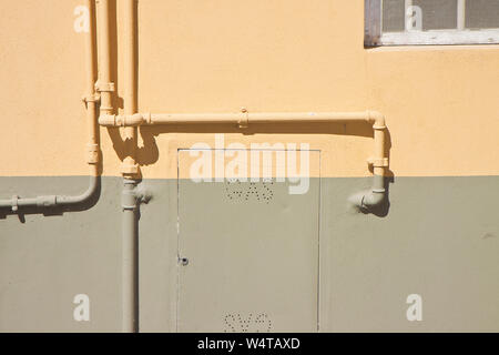 External metal and copper gas pipes, in front of an old plaster wall. Stock Photo