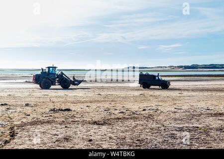 A JCB digger and Land Rover on the sandy beach at Instow, Devon, UK Stock Photo