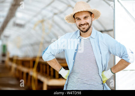 Portrait of a handsome farmer standing in front of the hothouse on a farm with snail breeding outdoors Stock Photo