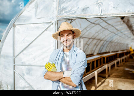 Portrait of a handsome farmer standing in front of the hothouse on a farm with snail breeding outdoors Stock Photo