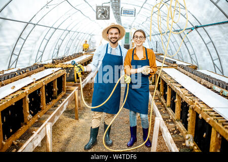 Portrait of a happy workers standing in the hothouse on a farm for growing snails. Concept of farming snails for eating Stock Photo