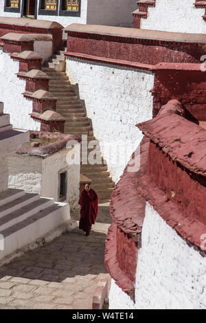 China, Tibet, Lhasa, A monk walks up a steep cobblestone walkway in the Ganden Buddhist Monastery which sits at the top of a natural amphitheater on Wangbur Mountain. It  founded in 1409 AD but was mostly destroyed in 1959 by the Chinese military. Stock Photo
