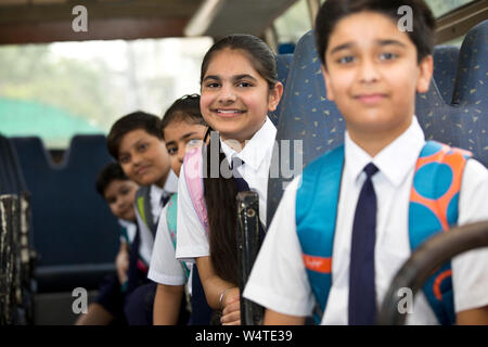 School children traveling in school bus looking at camera Stock Photo