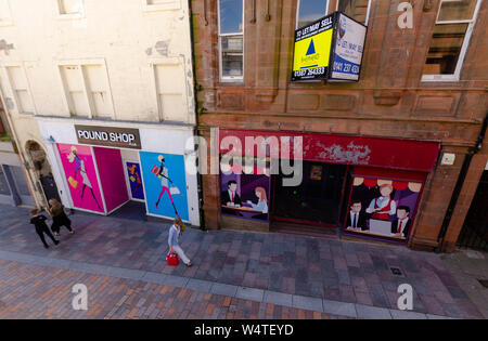 People pass by empty retail units in the High Street in Dumfries Scotland UK. Artwork has been painted on them as they have not been let for some time Stock Photo