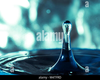 Close-up of a water drop impact with water surface, causing rings on the surface. Stock Photo