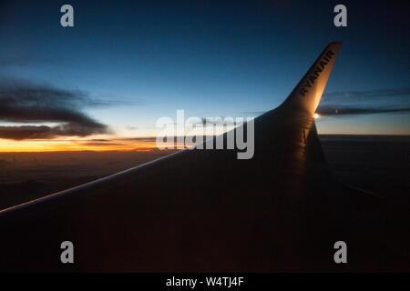 An evening view from the plane window to the wing of the plane. Stock Photo