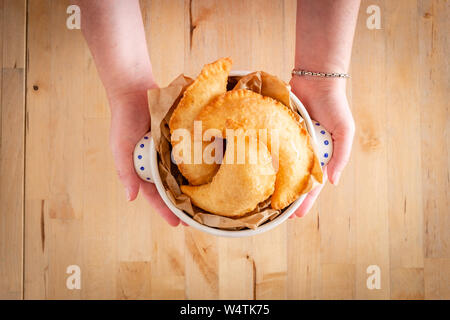 Female hands holding a bowl full of fried panzerotto. Traditional food of Puglia, Italy Stock Photo