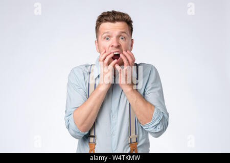 Young man covering mouth with hands and round eyes experiencing deep astonishment Stock Photo