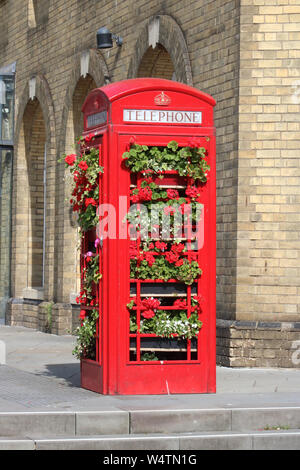 Recycled iconic British red telephone box now in use as a plant display holder in Bath city centre outside Bath Spa station on sunny day in July 2019. Stock Photo