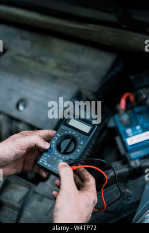 cropped view of auto mechanic holding measuring device in car service Stock Photo