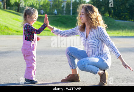 Happy young woman sitting playing with little girl clapping hands Stock Photo