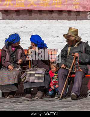 China, Tibet, Lhasa, Tibetan Buddhist pilgrims from the Kham region of eastern Tibet circumambulating around the Jokhang Temple  the man wears the traditional golden thread hat and the women wear their pangden or bangdian aprons  All are carrying their mala rosary beads. Stock Photo