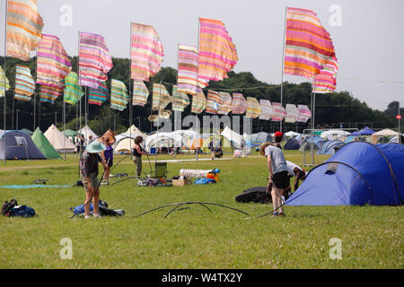 Malmesbury, Wiltshire, UK. 25th July 2019. Festivals goers arrive as a heatwave bakes the countryside. Despite the heat the party revellers are in high spirits and eager to set up camp for the 37th WOMAD Festival (World of Music, Arts and Dance) held in the beautiful grounds of the Charlton Park Estate. Credit: Casper Farrell/Alamy Live News Stock Photo