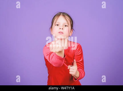 Do not even touch me. Aggressive face small girl violet background. Lost emotional control. Girl little child emotional face expression. Angry and emotional. Threatening violence. Desperate baby. Stock Photo