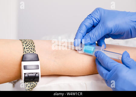 Close-up shot of doctor or nurse ready to take a blood sample from arm vein with a vacutainer. Venipuncture or venepuncture procedure Stock Photo