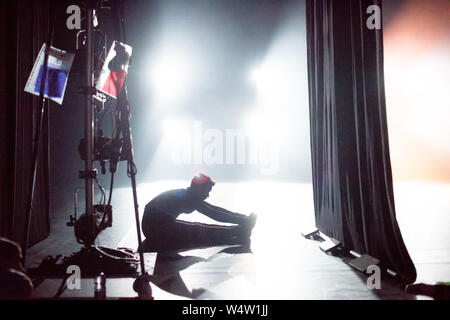 Dancer sitting on the floor warming up in the wings before a performance. Stock Photo