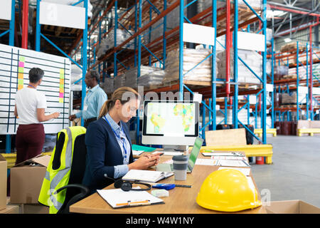 Female manager using mobile phone at desk Stock Photo