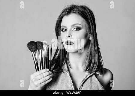 Makeup cosmetics concept. Skin tone concealer. Cosmetics shop. Girl apply eye shadows. Woman applying makeup brush. Emphasize femininity. Professional makeup supplies. Skin care. Different brushes. Stock Photo